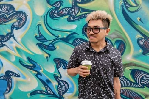 Asian man holding drink - Australian Stock Image