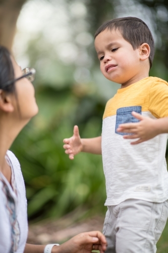 Asian mother comforts her crying 2 year old son - Australian Stock Image
