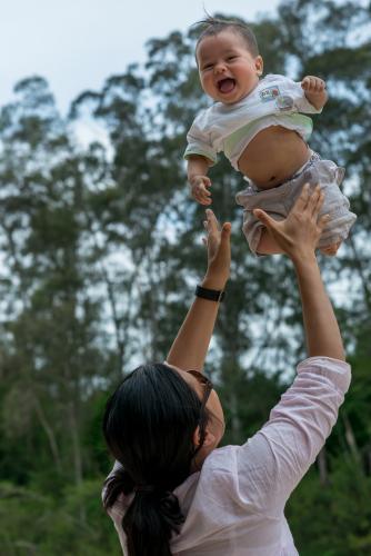 Asian mum throws her baby boy up in the air