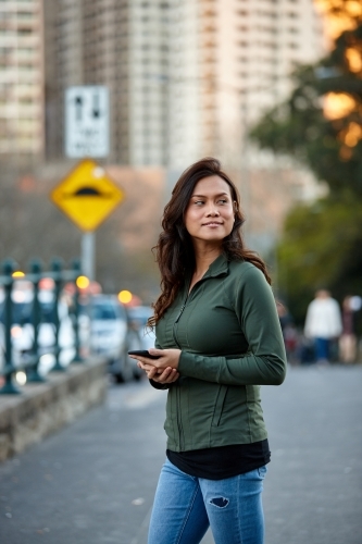 Asian woman at taxi stand with mobile phone - Australian Stock Image