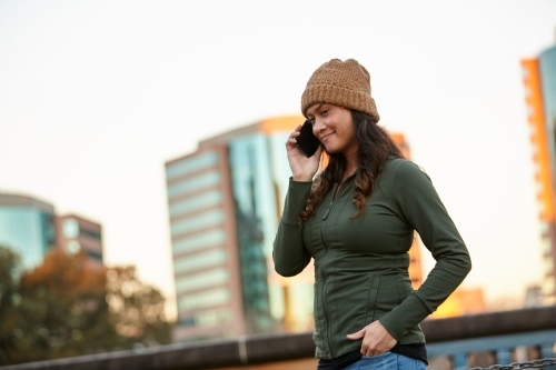 Asian woman smiling with mobile phone in city - Australian Stock Image