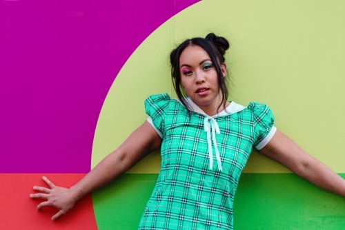 asian woman standing against colorful wall - Australian Stock Image