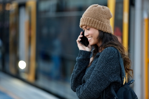 Asian woman talking on phone after getting off train - Australian Stock Image