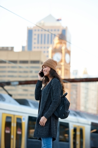 Asian woman talking on phone waiting at train station