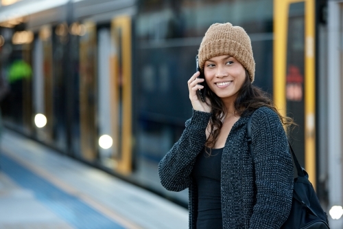 Attractive woman waiting at train station talking mobile phone - Australian Stock Image