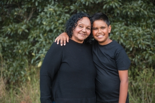 Aunty and boy looking at the camera smiling in the bush - Australian Stock Image