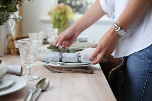 Close up of woman's hands setting Christmas table - Australian Stock Image