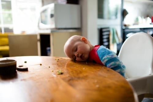 Baby asleep at the kitchen table - Australian Stock Image