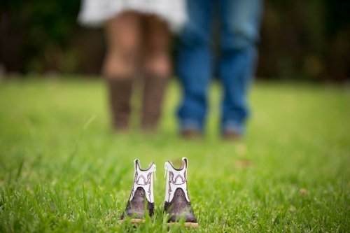 Baby boots with parents in blurred background - Australian Stock Image