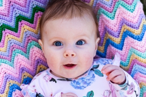 Baby with wide blue eyes and a surprised expression - Australian Stock Image