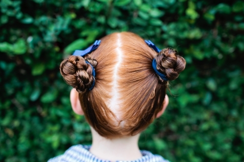 Back of a girls head with two buns in her hair - Australian Stock Image