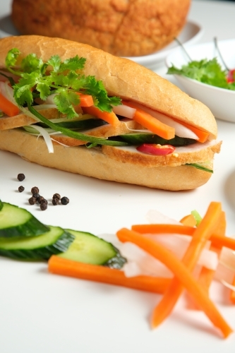 Banh mi with ingredients on white table