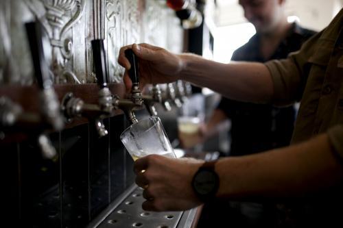 Bartenders pouring drinks on tap at local craft beer bar - Australian Stock Image