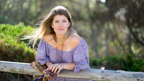 Beach girl leaning on railing looking at camera - Australian Stock Image