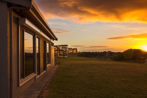 Beachfront shacks reflecting the rising sun - Australian Stock Image