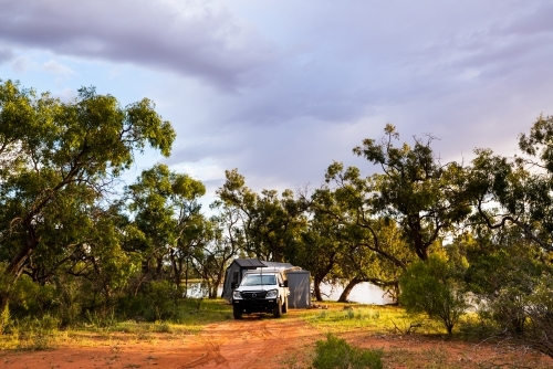 Beautiful campsite beside lagoon in golden dawn light with nice cloud formations - Australian Stock Image