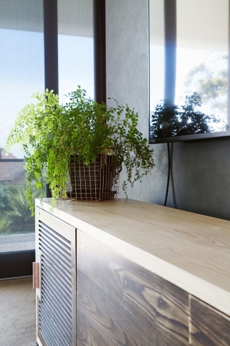 Bedroom buffet with copper wire basket indoor plant - Australian Stock Image