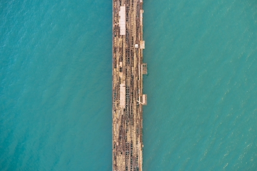 Bird's eye view of a derelict jetty cutting through clear ocean water - Kwinana Bulk Jetty - Australian Stock Image
