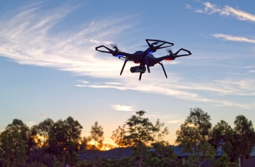 Black Drone flying at sunset in a park with copy space UAV, RPAs - Australian Stock Image