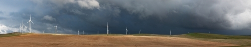 black storm clouds behind wind turbines - Australian Stock Image