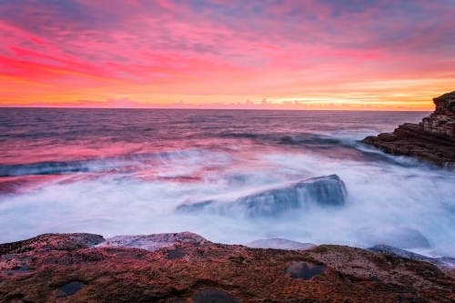 Blazing red pink orange and yellow sunrise skies over the east Sydney coastline