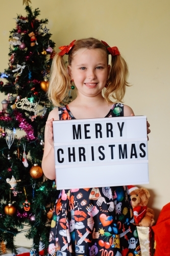 Blonde girl holding a Merry Christmas sign - Australian Stock Image