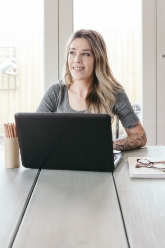 Blonde girl working at home contemplating something - Australian Stock Image