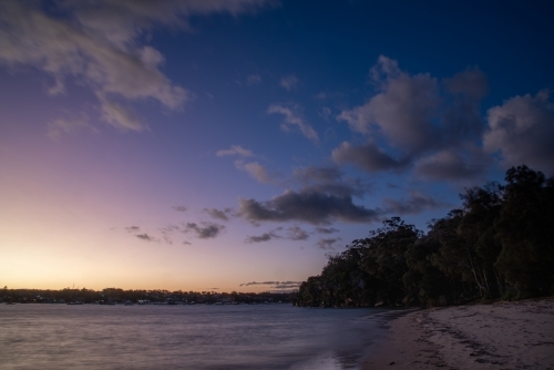 Blue hour photo of beach and bay with clouds in the sky - Australian Stock Image