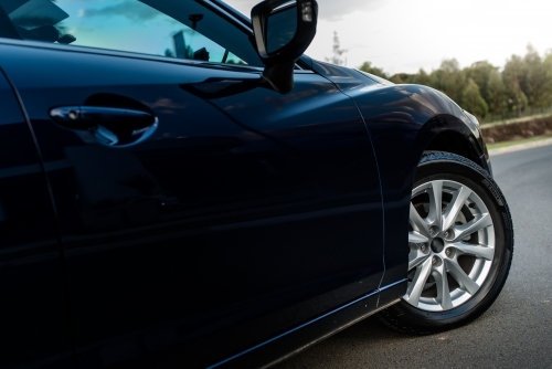 Blue station wagon on suburban street with luxury homes - Australian Stock Image