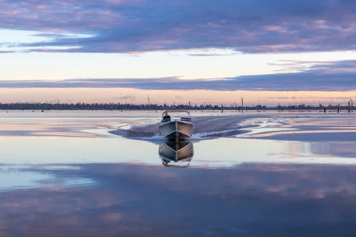 Boat moving through calm morning water - Australian Stock Image