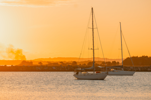 Boats moored on the Clarence River at Iluka in golden afternoon light with smoke haze from sugarcane - Australian Stock Image