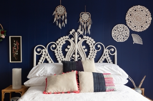 Boho cane bedhead on dark wall with lace styling - Australian Stock Image