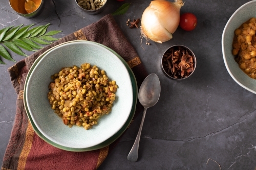 Bowl of Dahl Curry and ingredients around on dark background - Australian Stock Image