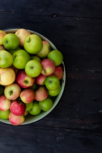 bowl of organic apples on a dark wooden background - Australian Stock Image