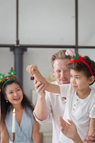 Boy holding cherry with help of parents - Australian Stock Image