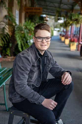 Boy in black glasses sitting on a railway platform - Australian Stock Image