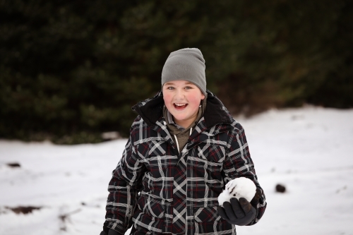 Boy in the snow with snow ball having snowball fight - Australian Stock Image