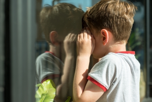 Boy looking into window with reflections - Australian Stock Image