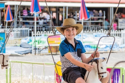 Boy on horse ride at local show wearing akubra hat smiling with thumbs up - Australian Stock Image