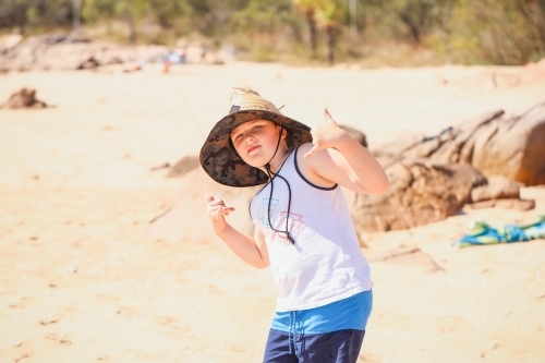 Boy on the beach wearing large straw hat at Cape Gloucester in the Whitsundays - Australian Stock Image