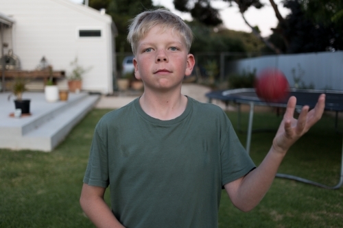 Boy playing backyard cricket at dusk - Australian Stock Image