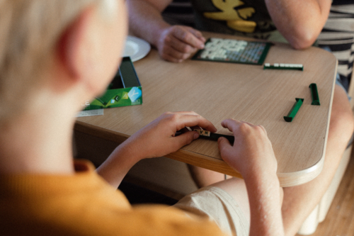 Boy playing scrabble game in caravan with father - Australian Stock Image