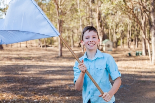 Boy playing with light blue flag in backyard - Australian Stock Image