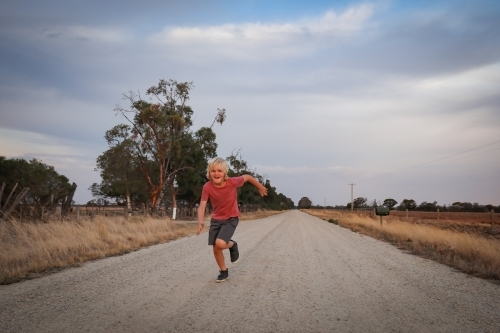 Boy running on dirt country road - Australian Stock Image