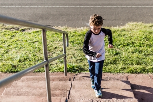 Boy running up steps - Australian Stock Image