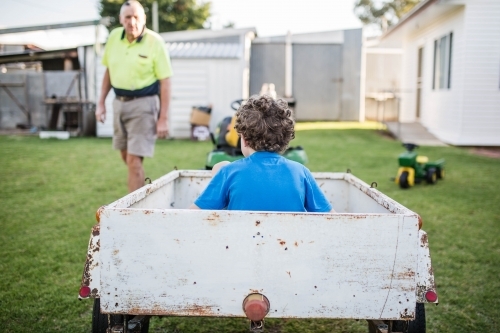 Boy sitting in white trailer talking to grandfather - Australian Stock Image