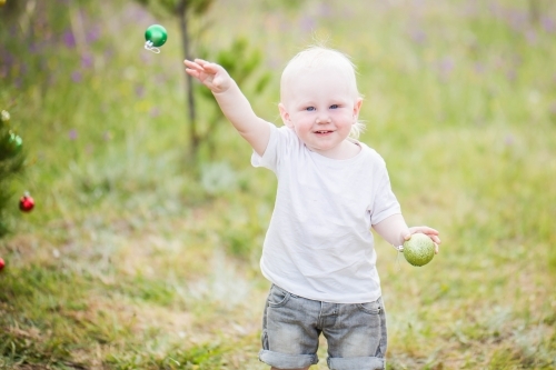 Boy smiling throwing Christmas bauble outdoors
