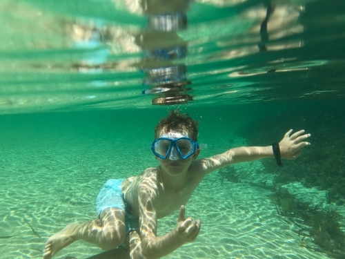 Boy underwater looking at camera wearing snorkeling mask - Australian Stock Image