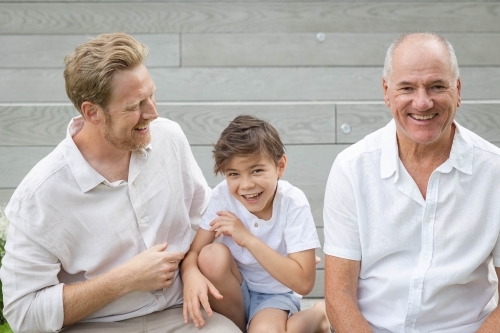 Boy with father and grandfather sitting on outdoor stairs - Australian Stock Image