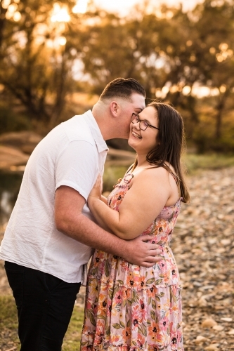 Boyfriend whispering in girlfriends ear as she laughs - Australian Stock Image